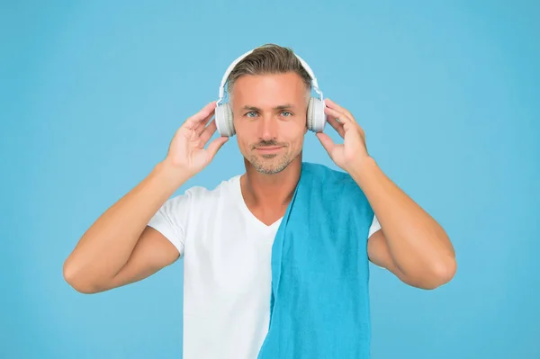 Exercício para música. Bonito homem desfrutar de música no fundo azul. O atlético ouve música nos auscultadores. Ouvir música melhora o treino. Treinamento em ginásio — Fotografia de Stock