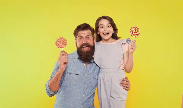 De hele dag gelukkig. Gelukkige familie gele achtergrond. Gelukkig eten vader en dochter lolly 's. Snoepwinkel. Veel plezier. Positief zijn. Vrije tijd en rusttijd. Genieten van de tijd samen. Je maakt me gelukkig. — Stockfoto