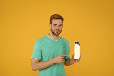 Görünüşü harika. Saçını köpükle yıkayan adam. Kuaför ve berber dükkanı. Tıbbi nemlendirici jel reklamı. Mükemmel banyo terapisi. Dükkan asistanı işaret ediyor. Adam şampuan şişesini tutuyor.