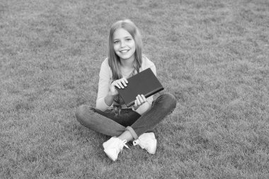 Açık havada kitap okuyan kız yeşil çimenlik arka plan, çocuk edebiyatı konsepti