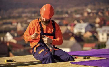 Düz çatılara buhar bariyerleri ya da yalıtım katmanları kurun. Çatı tamircisi. Ana onarım çatısı. Düz çatı kurulumu. Adam sert şapkalı, dış mekânda çalışıyor. Ev inşa ediliyor.