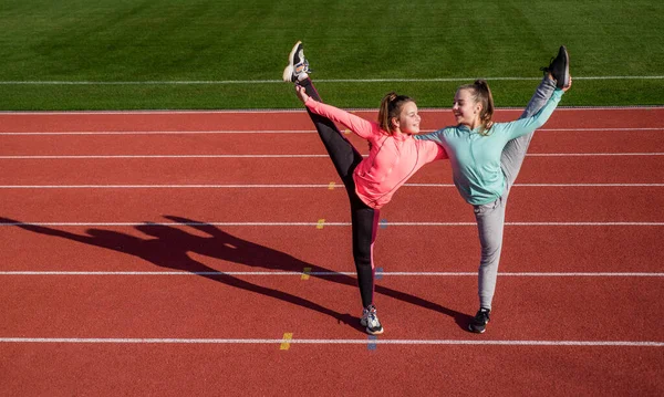 Mantener esos músculos flexibles. chicas adolescentes calentándose en el estadio. niños en ropa deportiva estirándose. los niños hacen ejercicio. una infancia saludable. entrenamiento al aire libre. gimnastas flexibles de confianza — Foto de Stock