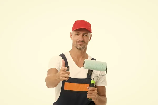 Wall painting is eco and economic. Paint rolling. Decorator hold paint roller. Wall painter. Paint work. Renovation and repair. Renewal and redecorating. Professional equipment. Mature man in cap — Stock Photo, Image