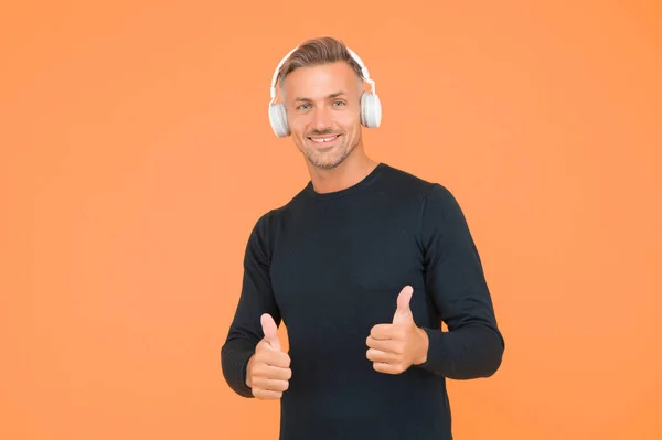 Sólo lo mejor. música y tecnología digital. ebook y elearning. chico sin afeitar en auriculares escuchando canción. lista de reproducción de aplicaciones musicales. dispositivo inalámbrico de calidad. hombre feliz con auriculares muestran el pulgar hacia arriba —  Fotos de Stock