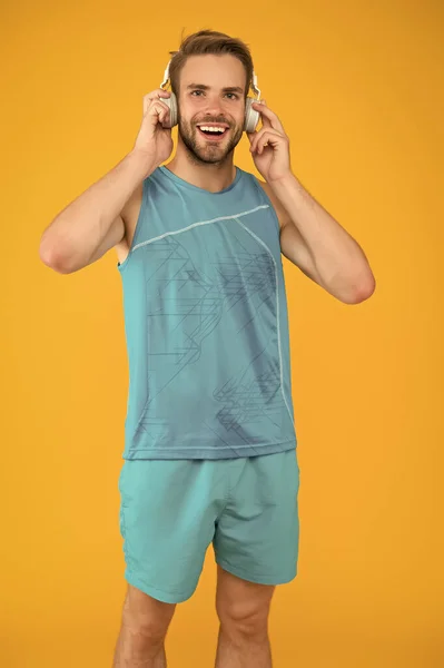 Homme beau sportif non rasé écoutant musique casque gadget. Casque sans fil pour le sport. Concept de casque moderne. Le sport est meilleur avec la musique. Entraînement confortable avec la liste des pistes préférées — Photo