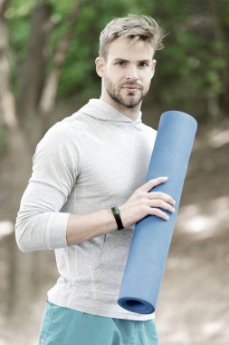 Park 'ta yoga yap. Sporcu her zaman antrenmandan sonra esneme hareketleri yapar. Sporcu açık hava eğitimi için spor minderi taşır. Açık hava yoga konsepti. Kendine güveni olan bir sporcu, esnemeye giden bir minder taşır.