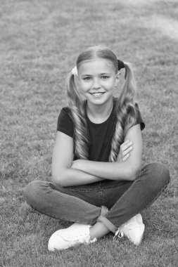 Küçük tatlı kız at kuyruğu saç stili yeşil çimlerde rahatlama, çocuk bakımı konsepti.