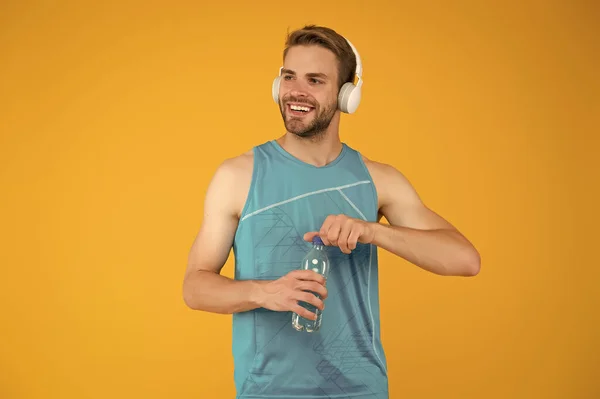 Celebrando la salud. Un hombre sano abre la botella de agua. El entrenador de fitness usa auriculares. Agua e hidratación. Beneficios para la salud. Aumento del nivel del agua y la salud. Aptitud para la resolución de salud —  Fotos de Stock