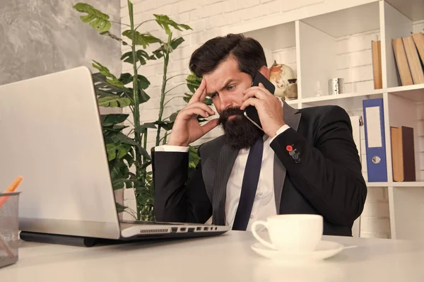 Stile di vita impegnato. Un uomo d'affari impegnato che parla al telefono. Un uomo barbuto lavora in ufficio. Lavoro o affari impegnativi. Giornata di lavoro impegnativa. Comunicazione commerciale. Vita moderna — Foto Stock