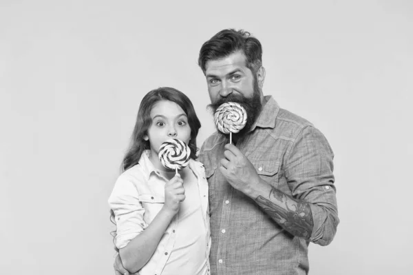 Gelukkig familie vader en dochter eten lolly gele achtergrond, zelfgemaakte karamel concept — Stockfoto