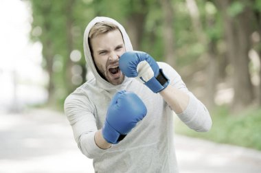 Boks antrenmanı dayanıklılığı. Spor eldivenleriyle boks yapan sporcu yüzlü bir adam. Boksör dövüşmeye hazır. Boks eldivenli sporcu boksörü eğitimi. Güzel yumruk.