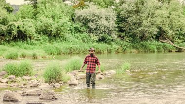 Tatmin olmuş balıkçı. Balıkçılık dikkatli olmanı ve tam olarak hazır bulunmanı gerektirir. Zalim bir adam nehir suyunda lastik bot giyer. Balıkçı erkek hobisi. Balıkçı ekipmanları. Balık oltaya geldi