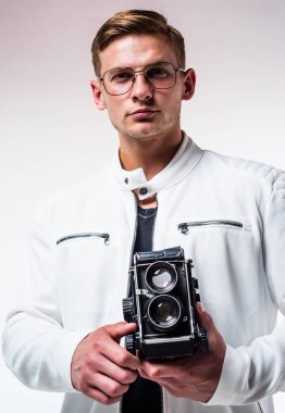 Beyaz kentsel kıyafetli genç adam eski kamera ve moda fotoğrafçısıyla fotoğraf çekiyor.
