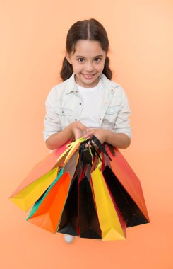 Alışveriş paketlerine bir bak. Bir sürü alışveriş torbası olan şirin bir çocuk. Kara Cuma indirimli. Alışveriş paketlerini alın. Kız alışveriş çantaları taşıyor. Sarı arka plan. Alışverişe düşkün kız