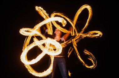 Seksi kadın oyuncu güzel ateş desenleri yaratır. Açık havada karanlık, ateş dansçısı.