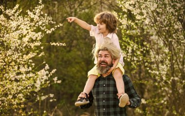 Mutlu bir aile. Küçük oğlum. Bahar yürüyüşü. Babalık. Babalar Günü. Doğada yaşayan küçük bir çocuk ve baba. Hipster ve küçük oğlu çiçek açan bahçede. Sakallı zalim adam, iyi baba. Baba ve oğul.