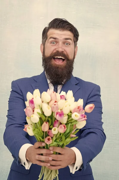 Spring holidays. prepare for mothers day holiday. flower surprise for her. bearded man in formal suit greeting. happy valentines day. womens day gift tulips. spring flowers. Man with bouquet tulips
