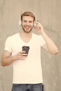 Onun sabahı müziğe adanmıştır. Mutlu adam kahve içerken müzik dinliyor. Yakışıklı adam müzik çalarken kulaklık takıyor. Yeni teknoloji. Modern hayat. Eğlence ve eğlence. Müzik ve içecek.