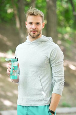 Açık hava antrenmanından sonra vitamin içeceğini tazeliyorum. Adam atletik görünüşte su şişesi tutuyor. Sporcu erkek sporcu idmandan sonra şişeye su döker. Sporcu parktaki eğitimden sonra su içer