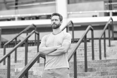 Yakışıklı sakallı adam kendine güvenerek ayakta duruyor. Formda ve sağlıklı kalmak. İyi bir spor şekli var. O her zaman formdadır. Ciddi sakallı adam ellerini çapraz yaptı. Kendine güvenen ve başarılı