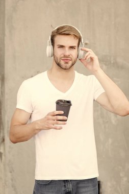 Kahve tüketimi onu daha mutlu ediyor. Yakışıklı adam kağıt bardak yapmak için kahve içer. Kafe konsepti. Kahve dükkanı. Adam taze demlenmiş kahveyi seviyor. Günlük kafein miktarı. Müzikle yürümek. Parçayı atla