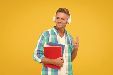 Ses kursları. İngilizce öğreniyorum. Modern teknoloji. Ses kitabı konsepti. Dünya çapında bilgi erişimi. Ses kütüphanesi. Yakışıklı öğrenci kulaklık takıyor ve kitap tutuyor. Dil çalış. Boş kurslar