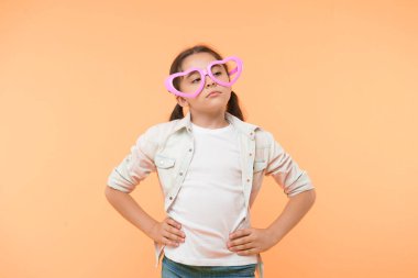 Umrumda değil. Çocuk sakin, umursamaz, sarı arka plan. Mutsuz çocuk duygularını belli etmek istemiyor. Kalp şeklinde gözlük takan çocuk Sevgililer Günü 'nü kutluyor. Sevimli kız sakin surat kalp gözlüğü