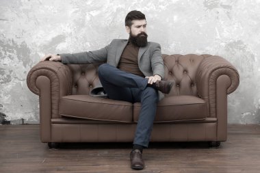 Zarif ve kendinden emin. Moda adamı. Manken koltukta dinleniyor. Sakallı adam sıradan moda tarzından hoşlanıyor. Modaya uygun bir iş adamı. İş ve moda