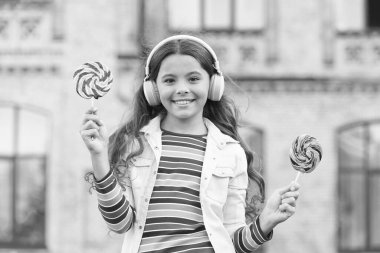 Neşeli kız modern kablosuz kulaklıklar şeker yer, tatlı çocukluk konsepti