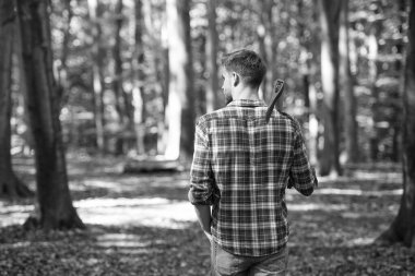 Ormanda balta ve doğa ile yürüyen ormancı.