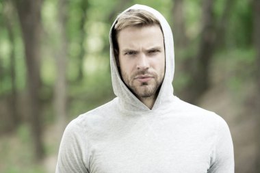 Maço adam. Kapüşonlu adam. Sıradan bir tarz. Erkek modası. Dışarıdaki traşsız adam. Ciddiyet ve erkeklik. Spor giyim modası. Sporcu dışarıda antrenman yaptıktan sonra rahatlar. Başlıklı yakışıklı, tıraşsız adam.