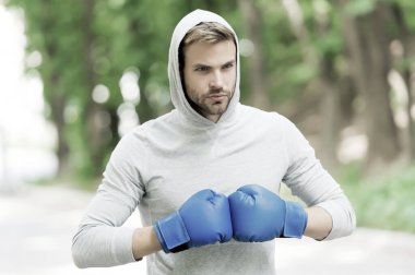 Savaşmaya hazırım. Konsantre yüzlü sporcu, spor eldivenli boks antrenmanı yapan, doğa geçmişi olan. Boksör başlığı dövüşmeye hazır. Boks eldivenli sporcu boksörü eğitimi