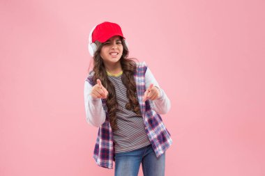 Şuna bak. Yeni teknoloji. Şapkalı ve kulaklıklı mutsuz genç kız. çocuk gündelik moda tarzı.