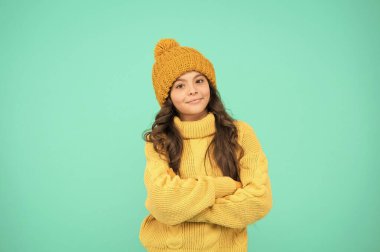 Güzel bir gün. Kendini sıcak tut. Küçük kızın en sevdiği kazak. Şapka ve eldivenler aksesuar. Mutlu çocuk turkuaz duvar. Grip yok. Kış için hazırlan. Kış tatili Ev yapımı örgü. Soğuk mevsim modası