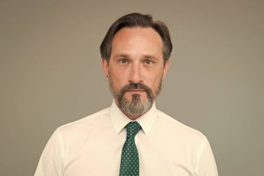 Klas bir örnek. Yakışıklı, kendine güvenen, olgun model beyaz gömlek giyiyor. Özgüven duygusu. Beyefendiler. Erkek modası. Moda dükkanı. Sakallı, olgun bir yüz.