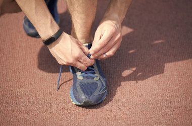 Ayakkabı bağcıklarını düzgün bağlıyorum. Bağlama ve Bağlama Koşu Ayakkabıları. Erkek eli dantelli spor ayakkabı. Atletik ayakkabılar. Ayakkabı mağazası. Aktif yaşam tarzı. Yay yapmak için ayakkabı bağını etrafına sararak güçlü bir düğüm atıyorum.