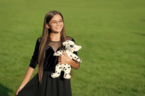 The joy of best things. Happy child hold toy dog on green grass. Pet animal. Friends and friendship. Playing games. Child care and childhood. International childrens day, copy space