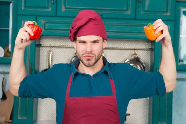 Şef şapkalı, önlüklü, kırmızı ve turuncu biberli adam.