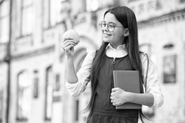 Elma günde bir doktoru uzak tutar. Küçük çocuk dışarıda elma ve kitap tutuyor. Elmalı kurabiye. Okul yemeği. Sağlıklı yemek ve diyet. Organik ve doğal beslenme. Sağlık eğitimi. Vitamin almak için doğru yol