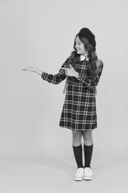 Fransız bereli çocuk sarı arka planı işaret ediyor. Şık bir genç üniversite öğrencisi. Sırt çantalı küçük kız okula gidiyor. Eğitim konsepti. Okul ve moda. Öğrenci üniformalı çocuk.