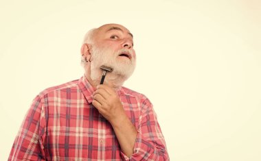 Beyaz sakallı, olgun bir adam. Kes ve saç fırçala. Berber dükkanı konsepti. Traş aksesuarları. Tıraşsız yaşlı adamın bıyığı ve sakalı var. Tıraş bıçağı alet çantası. Boşluğu kopyala