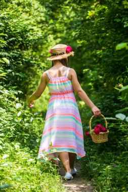 Yürüyen yeşil orman. Genç kız hasır şapkayla yürüyor. çocukluk mutluluğu. yaz tatili.