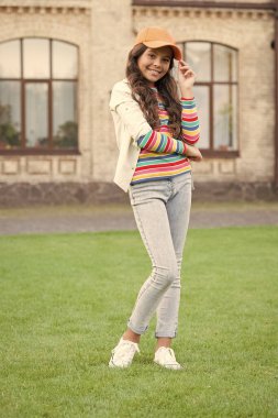 Mükemmel tarzı. Bahar modası ve güzellik. Mutlu çocuklar günü. Şapkalı şık bir çocuk. Sıcak bir gülümseme. Sağlıklı yaşam tarzı kavramı. Küçük kızın kıvırcık saçları var. Güzel esmer çocuk sokakta