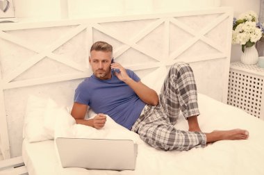 Sabah titreşimleri. Adam dizüstü bilgisayarda çalışıyor. Online kurslar evde eğitim. İpuçlarını kilitle. Bir şeyler alıp internetten alışveriş yapmak. Adam yatakta telefonu kullanıyor. İletişim ve insan konsepti. çevik iş