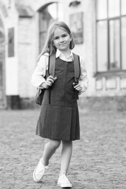 Resmi üniformalı küçük çocuk okula çantasıyla gider, okula geri döner.