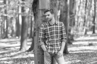 Ne güzel bir gün. Ormandaki kaslı adam. Açık havada düğmesiz gömlekli seksi maço. Tıraşsız adamın saçları taranmış. Erkek güzellik ve moda. Tüylü adam kareli gömlek giyiyor. Sıradan moda tarzı