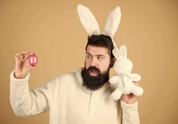 Easter rabbit. Man wearing rabbit suit. Funny bunny man soft ears. Easter activities concept. Weirdo concept. Celebrate Easter. Guy bearded hipster weird bunny with long white ears beige background