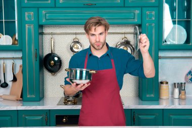 Aşçı adam tencereyi ve kapağı mutfakta tutuyor.