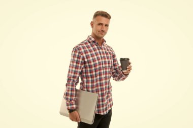 Başarıya doğru gidiyorum. Kahvenin tadını çıkaran yakışıklı bir adam. Dizüstü bilgisayarı ve kahve fincanı beyaz arka planı olan mutlu bir hipster. Kahve beni sabah uyandırır. Sıradan ofis çalışanı konsepti. Evden çalış.