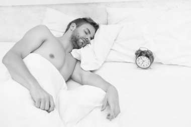 Uyuyan adam beyaz çarşaf ve kırmızı çalar saat, derin uyku konsepti.